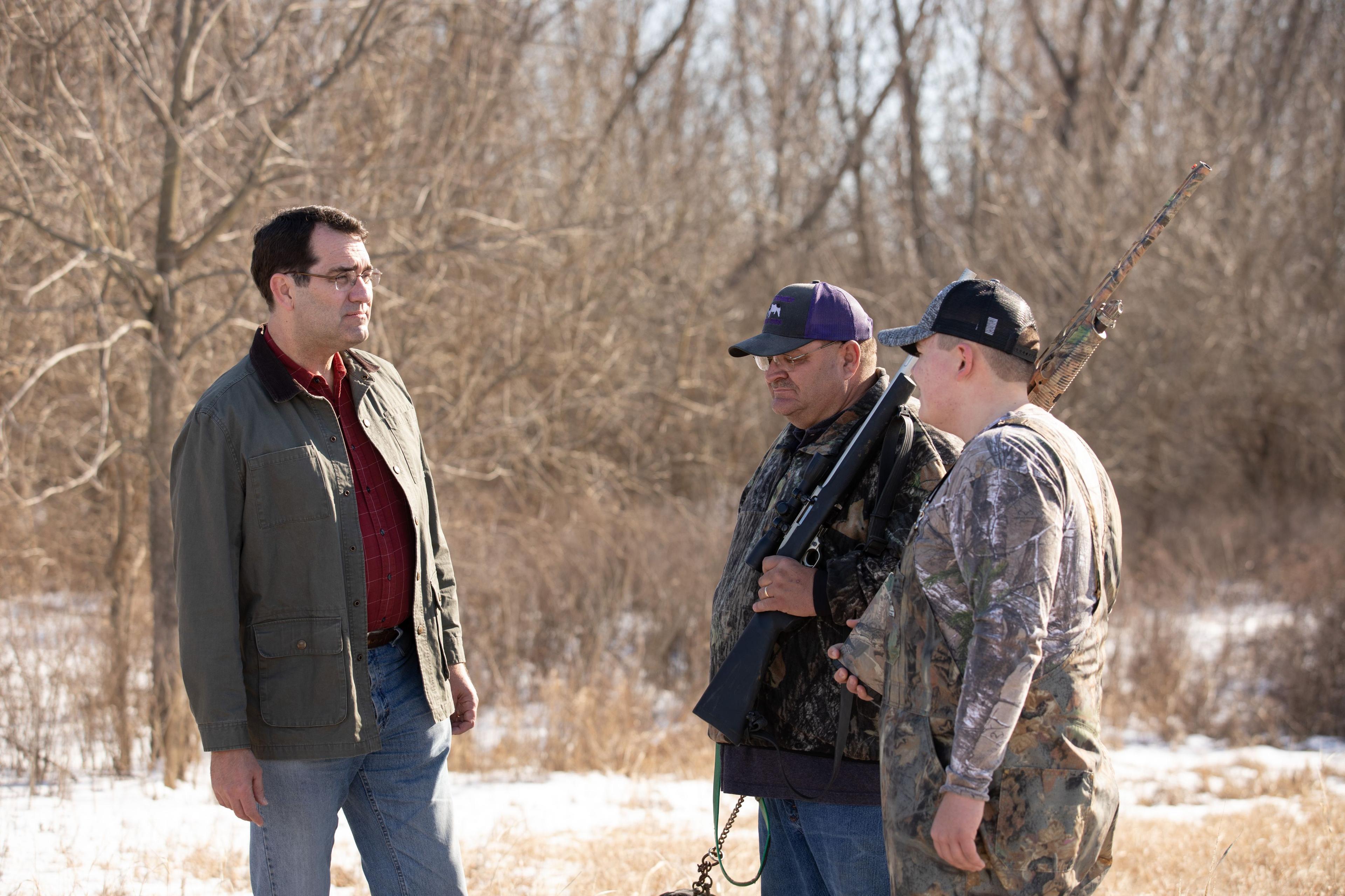 Derek Schmidt talking to a father and son outdoors